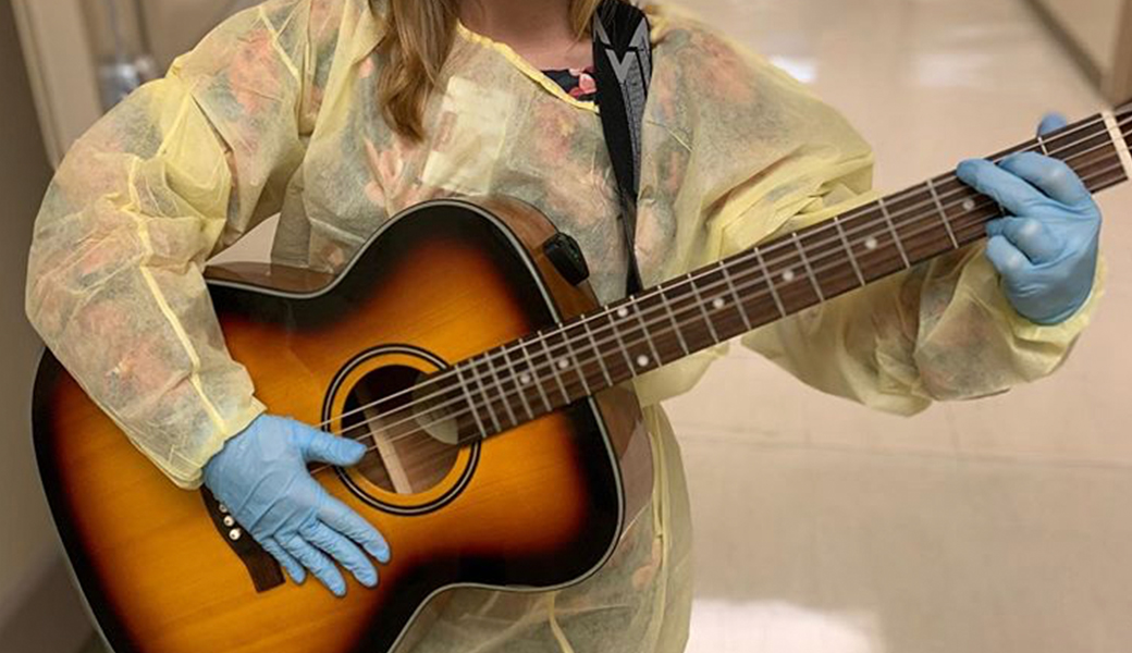 UA student holding a guitar and wearing medical attire